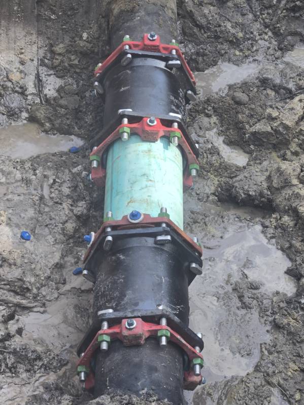 Mechanical pipe couplings with red clamps in trench